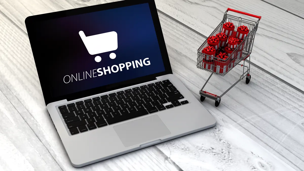 A laptop showing “Online shopping” next to a shopping trolley full of gifts